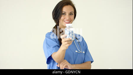 Junge braune kurzhaarige Arzt in Scrubs hält Flasche Stockfoto