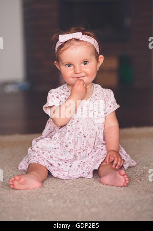 Kleines Mädchen auf dem Boden sitzend Stockfoto