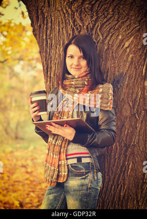 Mädchen hält Kaffee in Einweg-Cup und digital-Tablette. Vintage Foto Stockfoto