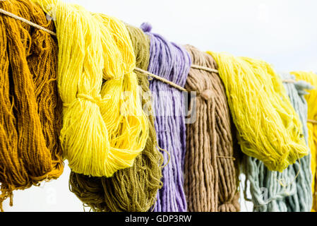 Hand von Seilen mit weißen Zelt im Hintergrund hängen Garn gefärbt. Stockfoto