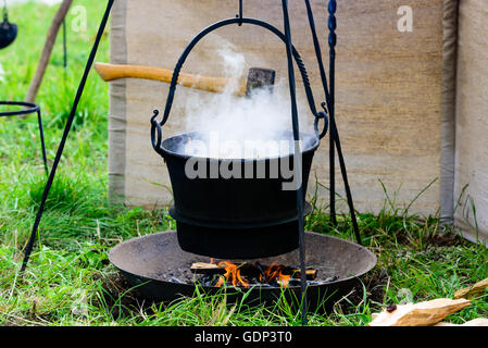 Heiße Eisen Hexenkessel hängend über offenen Feuer. Wasserdampf aus dem Topf. Kochen oder auf einem Campingplatz zu sterben. Stockfoto