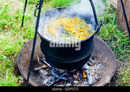 Im freien Hand an Garn in einem Eisentopf Kochen über offenem Feuer sterben. Garn und Kräuter in das kochende Wasser vorhanden. Stockfoto