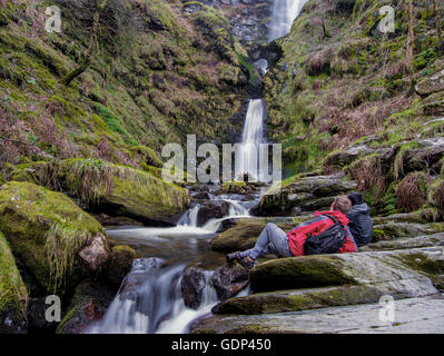 Zwei Wanderer ruhen neben dem Pistyll Rhaeadr Wasserfall, Wales. Stockfoto