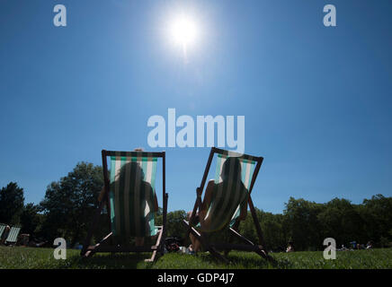 Menschen Sonnen Sie sich auf Liegestühlen im Green Park, London, als Großbritannien am heißesten Tag des Jahres so weit schmorte. Stockfoto