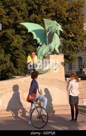 Studierende diskutieren vor dem Drachen Dragon Bridge, Ljubljana, Slovenia, Sonnenuntergang Stockfoto