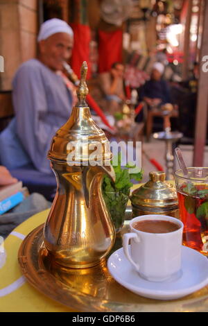 Im Inneren der Souk von Luxor, Ägypten, Pfefferminztee und arabischer Kaffee auf einem Kupfer Tablett, ein ägyptischer Mann Rauchen Shisha im Hintergrund Stockfoto