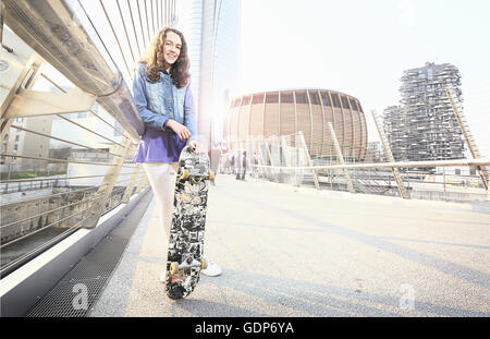 Mädchen mit Skateboard gelehnt Handlauf Stockfoto