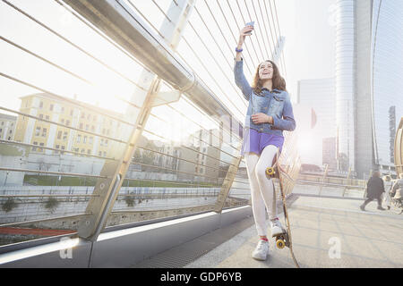 Mädchen mit Skateboard mit Smartphone zum Selfie nehmen Stockfoto