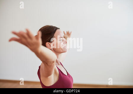 Seitenansicht der Frau in Übung Studio erhobenem Arm, schloss die Augen in Yogaposition Stockfoto