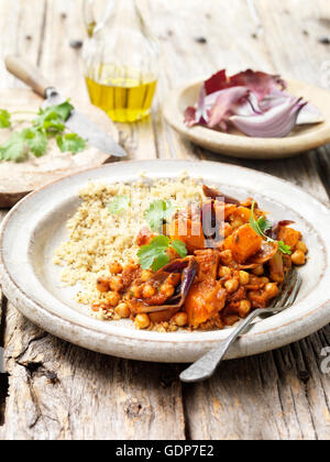 Vegetarisch essen gebratene Butternut-Kürbis rote Zwiebel Küken Erbsen Couscous Koriander Olivenöl rustikalen Holztisch Stockfoto