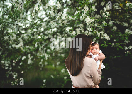 Über Schulter Porträt der Frau küssen Baby Tochter von Garten Apfelblüte Stockfoto