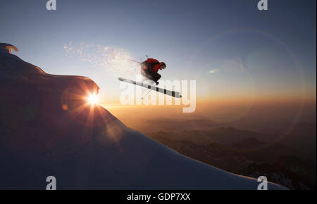 Skifahrer, die springen auf einen verschneiten Hang bei Sonnenuntergang, Zermatt, Kanton Wallis, Schweiz Stockfoto