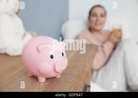 Mutter saß in Baby Kinderzimmer, Sparschwein auf Kommode Stockfoto