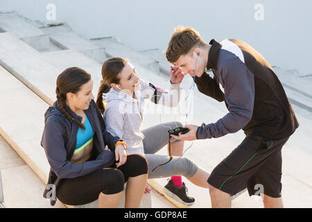 Drei Freunde, die eine Pause von der Ausübung, hören Sie Musik auf MP3-Player Stockfoto