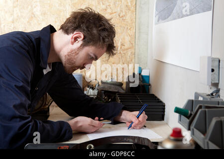 Männliche Mechaniker in Workshop, analysiert Computer Fahrzeugdaten, mit Handy Stockfoto