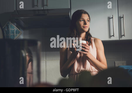Junge Frau mit einer Kaffeepause in Küche Stockfoto