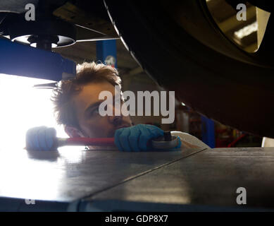 Männliche Mechaniker betrachten Achsvermessung an Sportwagen Stockfoto