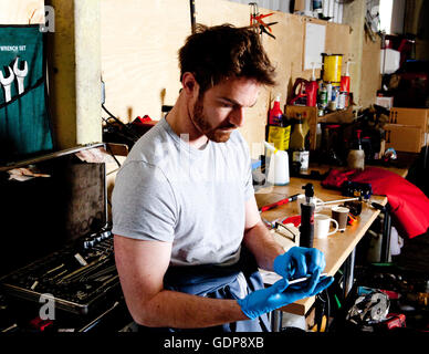 Männliche Mechaniker in Workshop, analysiert Computer Fahrzeugdaten, mit Handy Stockfoto