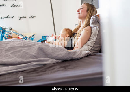 Müde, Frau und Baby Tochter liegenden Bett mit Kaffee Stockfoto