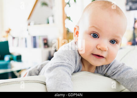 Blue eyed Babymädchen Klettern auf sofa Stockfoto