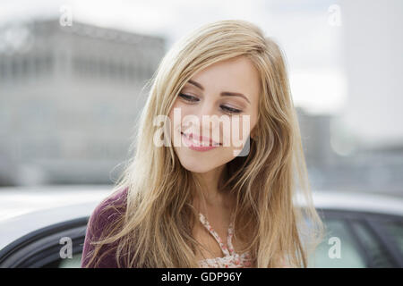 Schöne langhaarige blonde junge Frau in Stadt Stockfoto