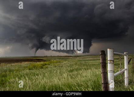 Ein großer Kegel Tornado landet in einem offenen Land Feld aus einer sehr großen schrägen Boden Schaben Wand Wolke Stockfoto