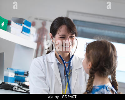 Weibliche pädiatrischen Arzt anhören eines jungen Mädchens Brust mit einem Stethoskop in einer Klinik Stockfoto