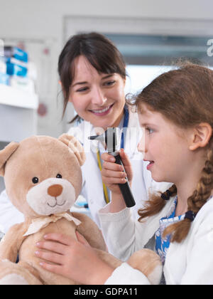 Mädchen mit Otoskop Teddybär prüfen Stockfoto