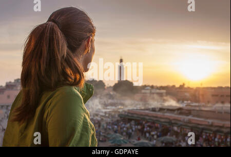 Rückansicht des Frau Blick auf Sonnenuntergang über Djemaa el-Fna Platz in Marrakesch, Marokko Stockfoto