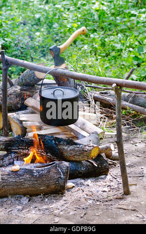 Tourist-Topf mit Wasser hängen über dem Feuer des Holzes auf dem Campingplatz. Stockfoto