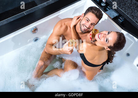 Schöne junge paar entspannende zusammen und trinken Champagner im Whirlpool. Stockfoto