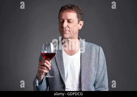 Ein Mann mittleren Alters halten und mit Blick auf ein Glas Wein Stockfoto