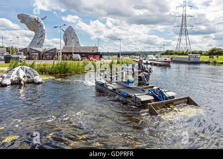 Grass in das Becken im Forth & Clyde Kanal in der Nähe der Kelpies im schottischen Falkirk Helix entfernt wird Stockfoto