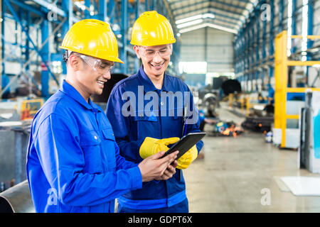 Zwei Arbeiter in der Produktion als Team diskutieren, industrial-Szene im Hintergrund Pflanzen Stockfoto