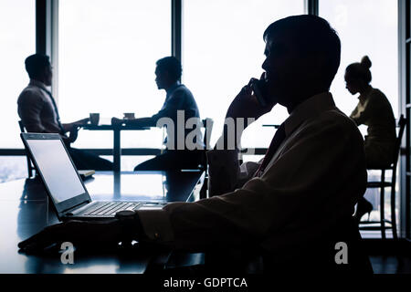 Arbeitssituation mit Mitarbeitern, Kaffeetrinken, reden und Geschäfte per Telefon, beleuchtete Silhouette erschossen Stockfoto