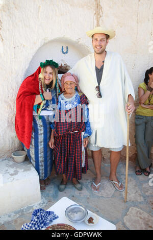 Paar gekleidet in ein Berber Kleidung mit einer Berber Frau vor einem Haus Höhlenwohnungen in Matmata, Tunesien. Stockfoto