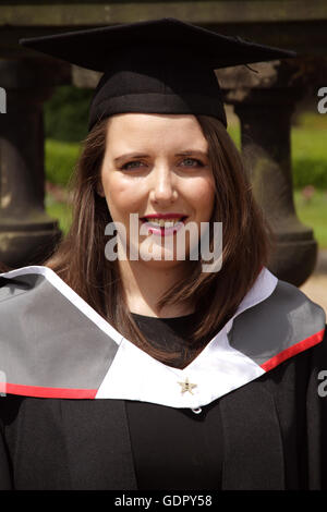 Nahaufnahme von einer hübschen jungen Frauen in Mütze und Mantel am Graduierungstag ihrer Stockfoto