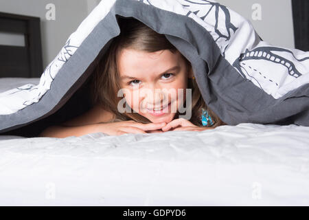 Kind oder Teenager unter erstreckt sich im Bett Stockfoto