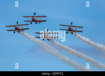 4 orange Boeing Stearman Doppeldecker, die Bestandteil der Breitling Wingwalker-Ausbildungs-Team in den Himmel Kunstflug zu tun. Stockfoto