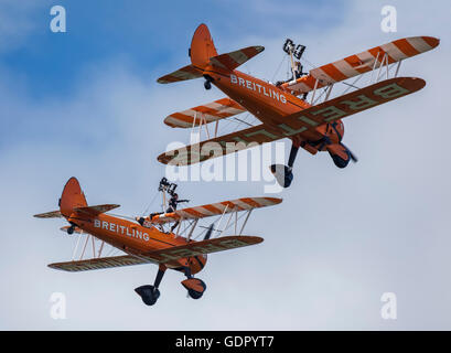 Zwei orange Boeing Stearman-Doppeldecker, die Bestandteil der Breitling Wingwalker Kunstflug Ausbildungs-Team im Flug Stockfoto