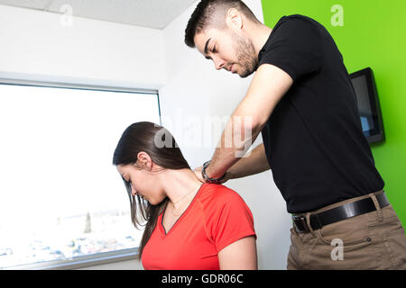 Frau sitzend und von einem Mann in Raum massiert Stockfoto