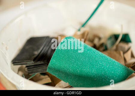 Nahaufnahme der Streifen von grünem und schwarzem Schleifpapier in einer kleinen weißen Kunststoff-Schüssel Stockfoto