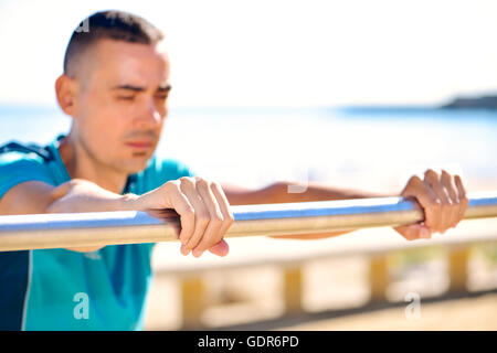 Nahaufnahme eines jungen kaukasischen Sportlers Sport Kleidung tun Steigung Liegestütze im Freien direkt am Meer Stockfoto