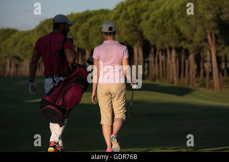 junges Paar zu Fuß zum nächsten Loch am Golfplatz. Mann Golf Tragetasche Stockfoto