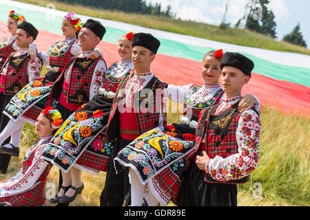 Rozhen, Bulgarien - 15. Juli 2016: Bulgarische Tänzer in Folklore-Kostüme-Areposign für ein Bild vor der bulgarischen Flagge Stockfoto