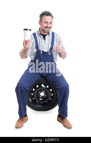 Gut aussehend Mechaniker in blauen Overalls zu tun, wie Geste und trinken heißen Kaffee isoliert auf weißem Hintergrund Stockfoto