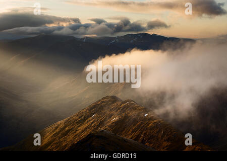 Der östliche Grat von Sgurr Fhuaran, der bei Sonnenaufgang von den fünf Schwestern von Kintail aus gesehen von einem dramatischen krepeskulären Strahl erillt wird Stockfoto