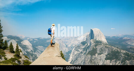 Junger Mann auf Felsvorsprung stehend, mit Blick auf den Half Dome, Blick vom Glacier Point, Yosemite-Nationalpark, Kalifornien, USA Stockfoto