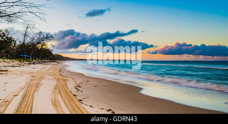 Der Strand auf North Stradbroke Island nachschlagen, wie die Flut kommt und die Sonne in der Ferne untergeht Stockfoto