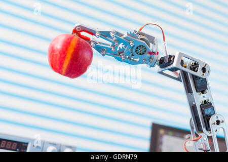 roter Apfel in einem Roboterarm Stockfoto